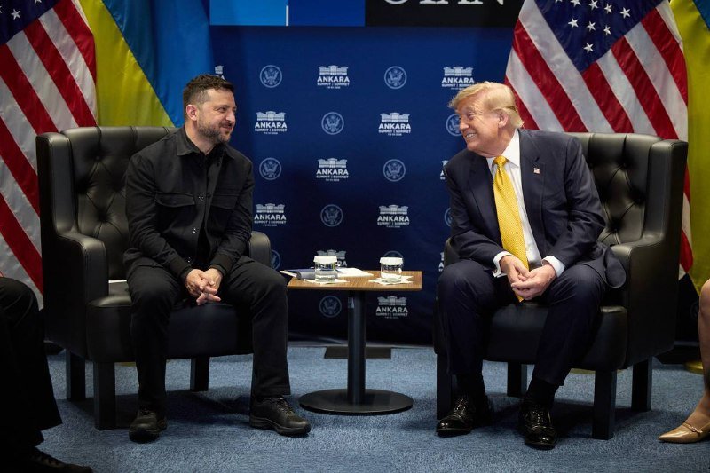 Two men in dark suits smile while seated across from each other in black armchairs, flanked by American and Ukrainian flags with a backdrop reading "ANKARA."
