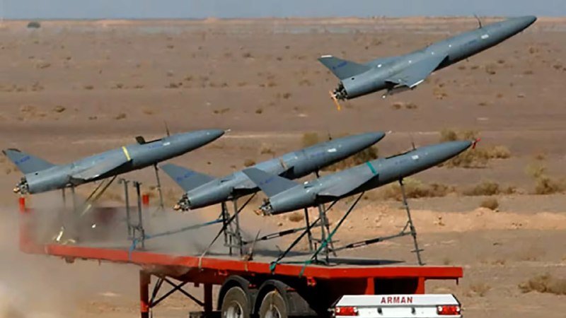A trailer labeled "ARMAN" in a desert launches multiple gray missiles from a mounted rack, with one mid-flight and dust kicking up behind.