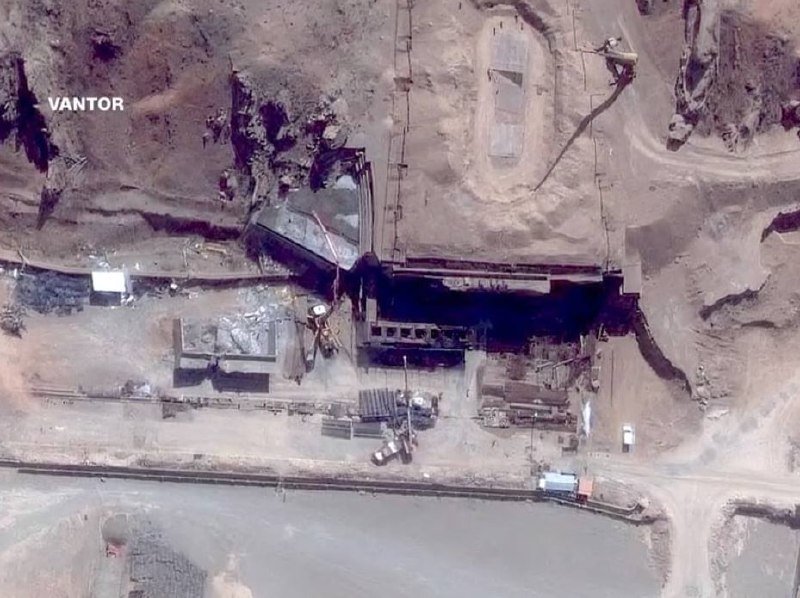 Satellite image labeled "VANTOR" shows an industrial site with excavated earth, structures, equipment, and a road in an arid landscape.