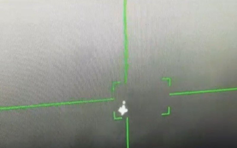 A blurry grayscale image shows green targeting lines and brackets centered on a small bright object against a dark background.