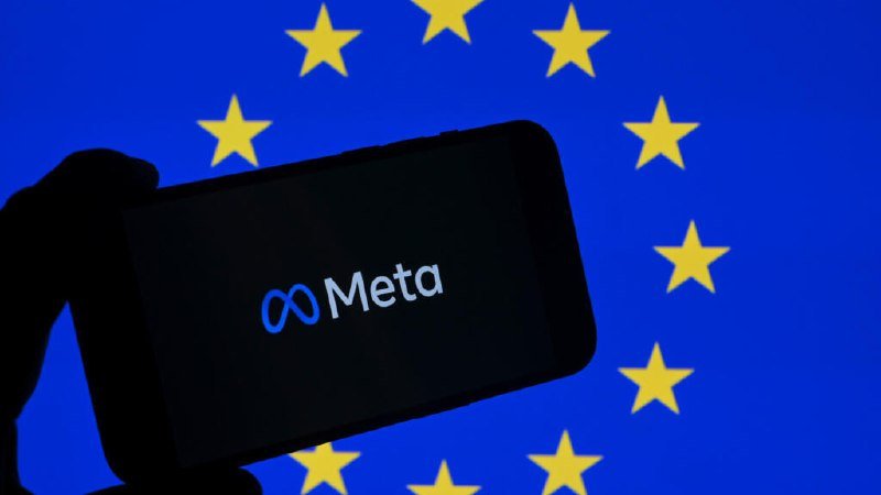 A silhouetted hand holds a smartphone displaying the Meta logo against a backdrop of the European Union flag's blue field and yellow stars.