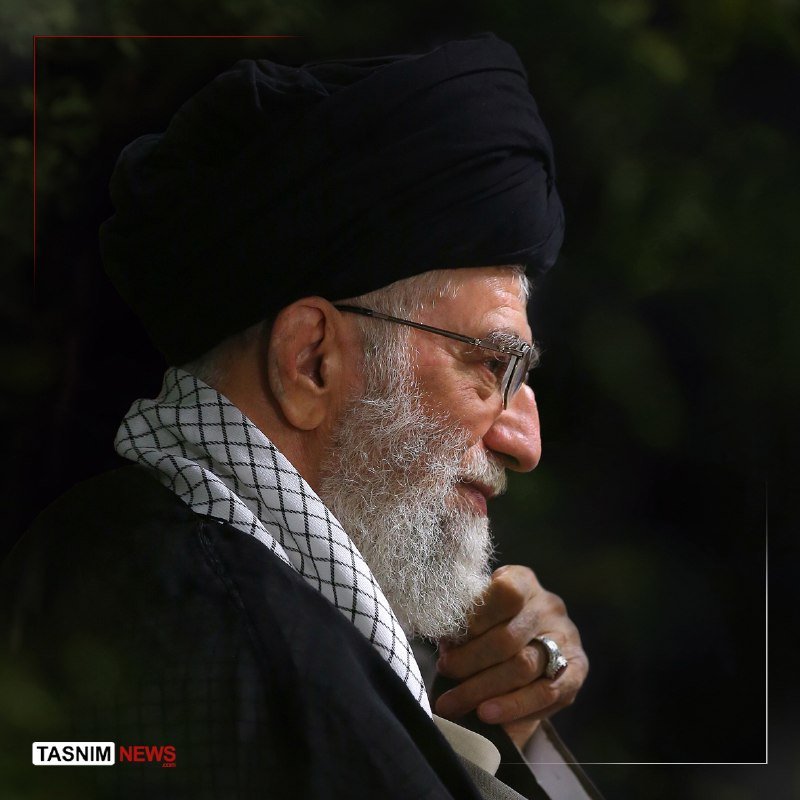 Profile of an elderly bearded man wearing a black turban, glasses, and checkered scarf, with a "Tasnim News" watermark visible.