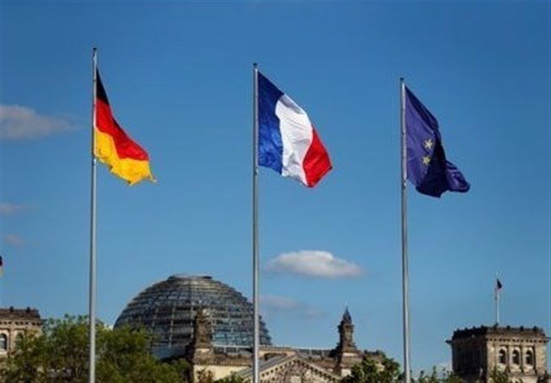 Three flags—German, French, and European Union—fly on tall poles against a blue sky above the Reichstag building's glass dome in Berlin.