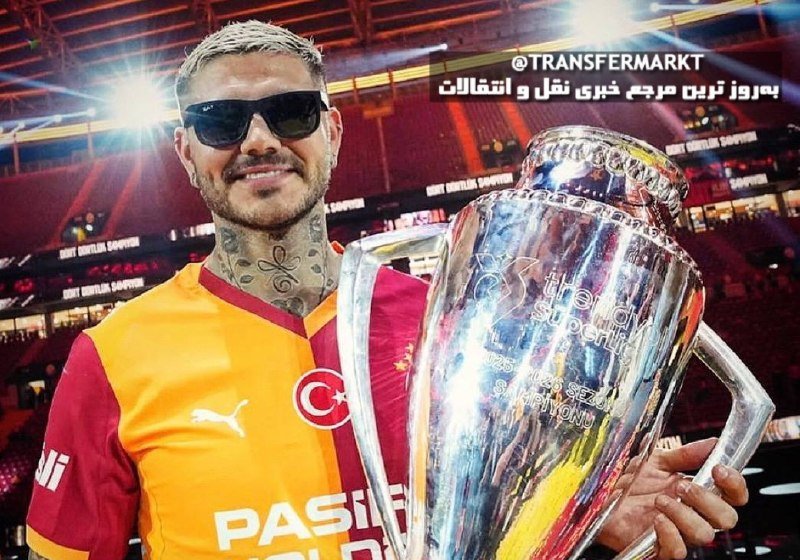 A tattooed man wearing sunglasses and a Galatasaray jersey holds the UEFA Super Cup trophy inside a stadium.