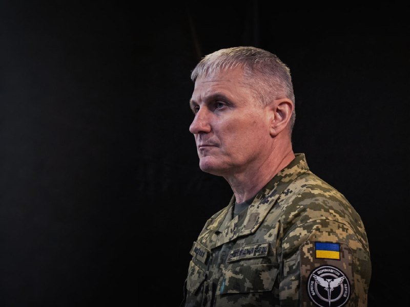 A man in a Ukrainian military camouflage uniform with a "Medical Forces Command" patch and Ukrainian flag looks off to the side against a dark background.