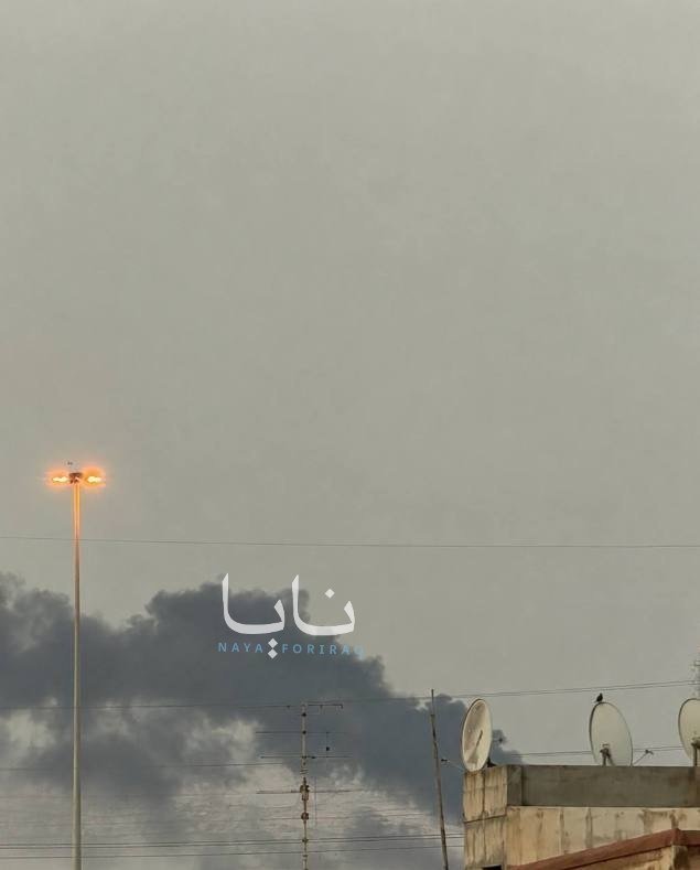 A tall streetlamp stands on the left against a hazy gray sky, with dark clouds, a power pole, satellite dishes, and a rooftop visible at the bottom.