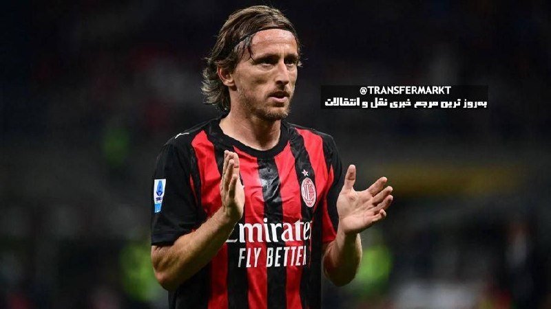 A long-haired footballer in an AC Milan red and black striped jersey claps his hands while looking to the side during a match.