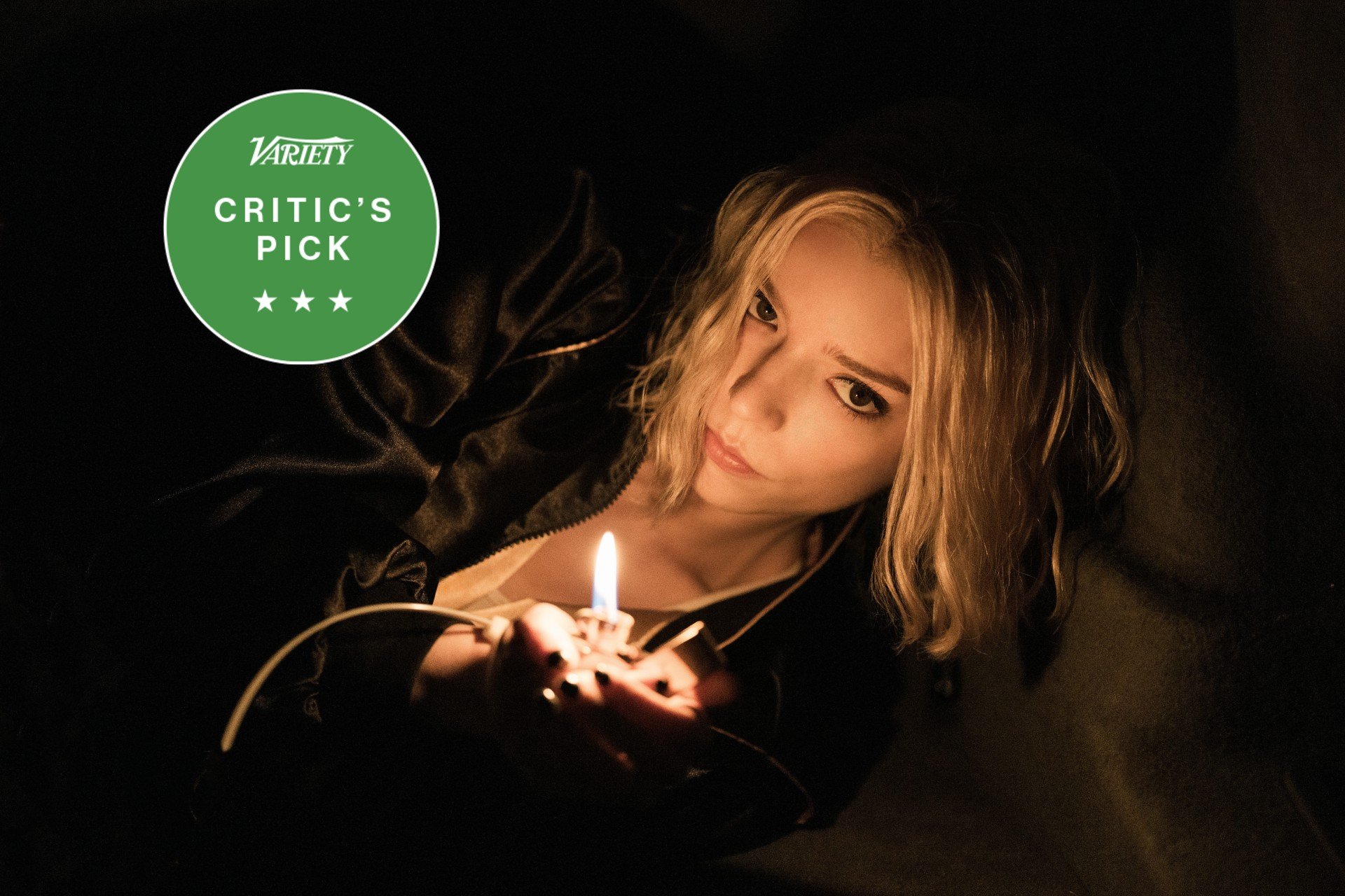 A blonde woman in a dark jacket holds a lit lighter in a dark setting, with a green "Variety Critic's Pick" badge displayed in the corner.