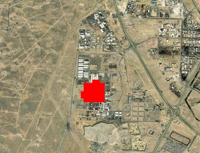 A satellite image shows a desert landscape with buildings, roads, and industrial structures, with a red block highlighting a specific area.