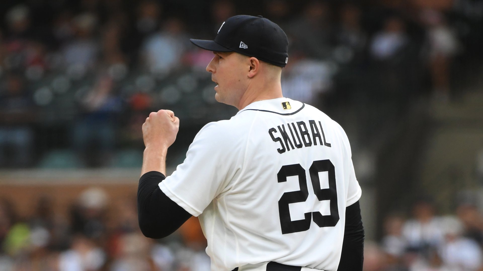 A baseball pitcher wearing a white jersey reading "SKUBAL 29" and a dark cap pumps his fist in celebration during a game before a blurred crowd.