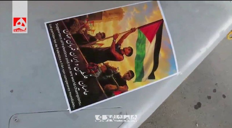 A printed poster showing figures holding a Palestinian flag and Hebrew text lies on a flat surface, with an "ABN" logo in the corner.