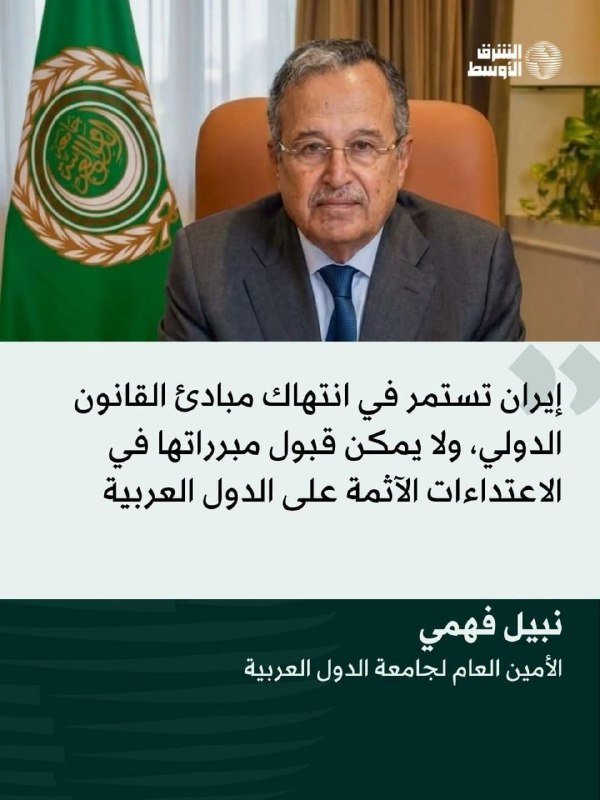 A man in a suit sits at a desk beside an Arab League flag, with Arabic text and a news network logo below.