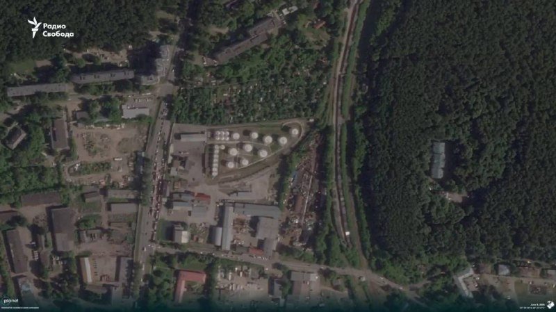 A satellite image shows an industrial facility with cylindrical storage tanks, railway tracks, and adjacent roads, bordered by dense forest, with a "Радио Свобода" logo in the corner.