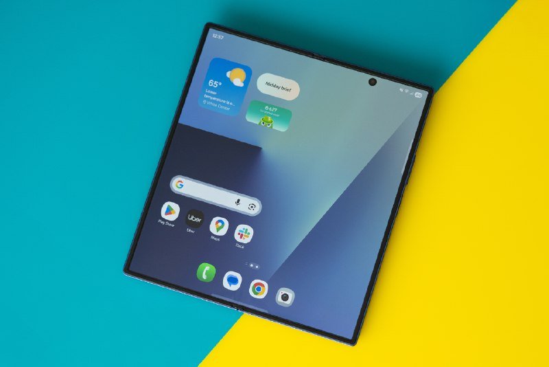 An unfolded smartphone displaying its home screen rests diagonally on a split teal and yellow background.