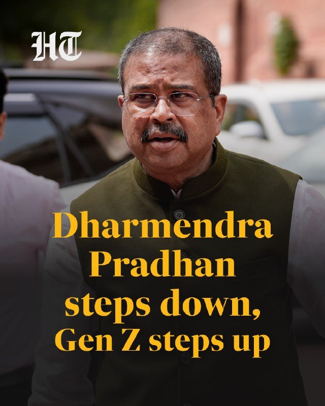 A man with glasses and a mustache, wearing a green vest, stands outdoors with parked white vehicles behind him, alongside overlaid text reading "Dharmendra Pradhan steps down, Gen Z steps up."