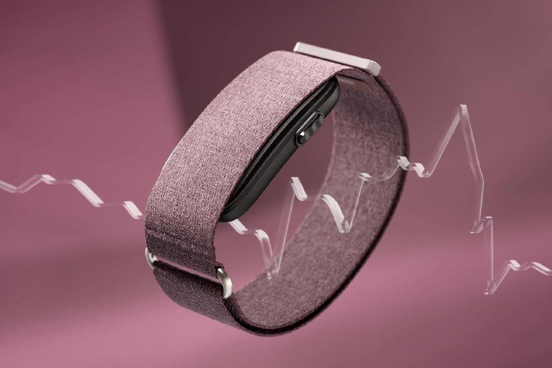 A wearable fitness band with a fabric strap and small button display floats against a pink background, flanked by stylized zigzag heartbeat lines.