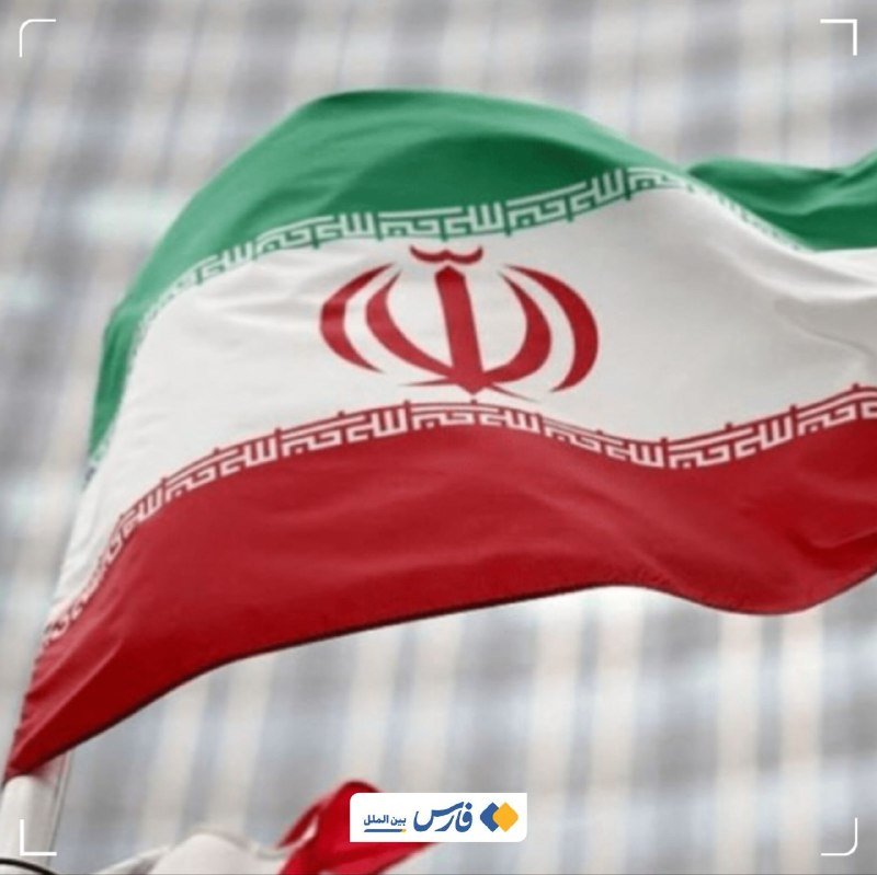 The flag of Iran, featuring green, white, and red horizontal stripes with a central emblem, waves against a blurred background.