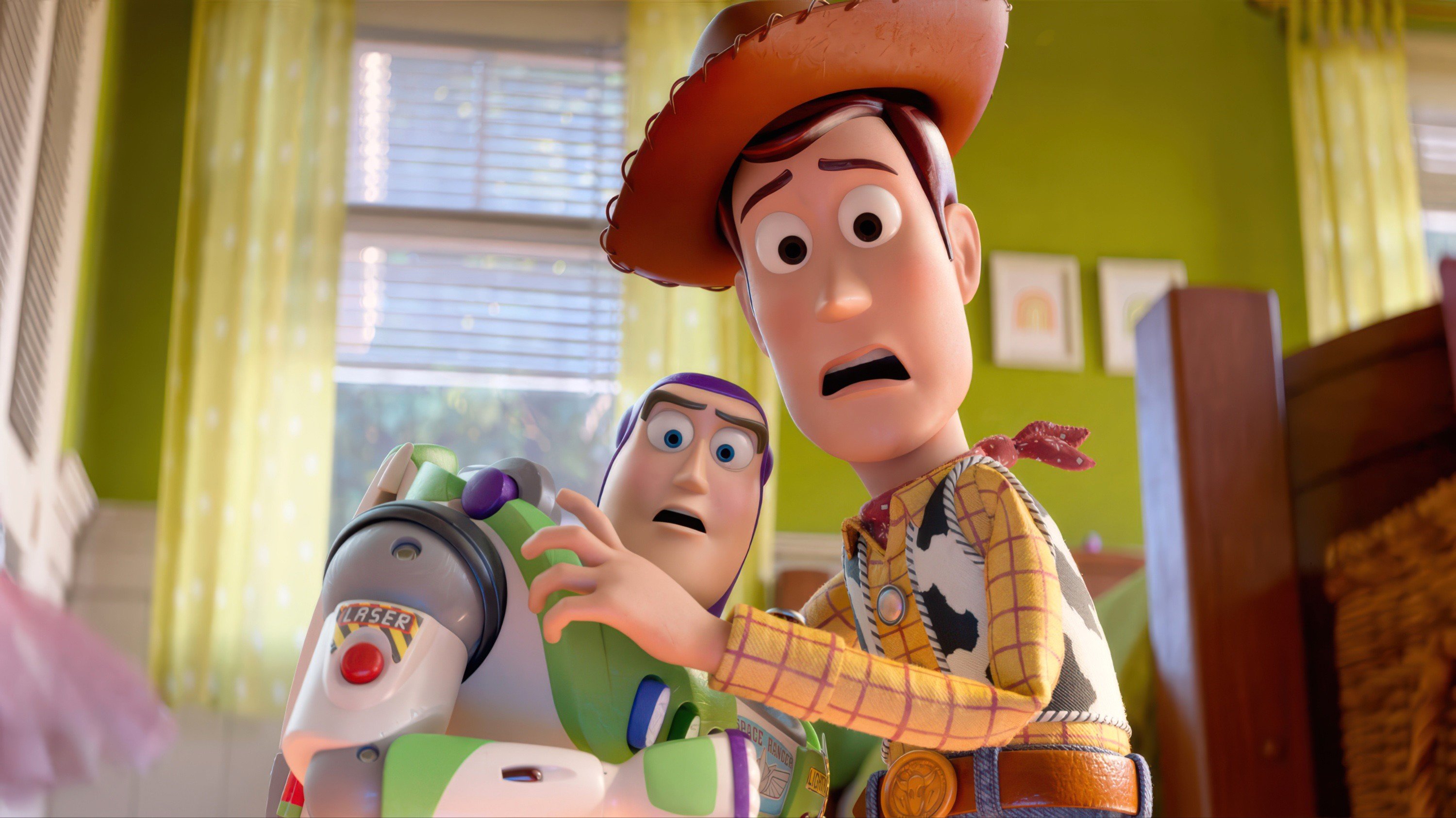 Two animated toy figures—a cowboy in a yellow plaid shirt and a space ranger labeled "LASER" and "SPACE RANGER"—stand together with worried expressions inside a room with green walls and yellow curtains.